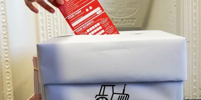 A hand putting a leaflets into a collection box. The leaflet is a hard copy of the information in farming survey.